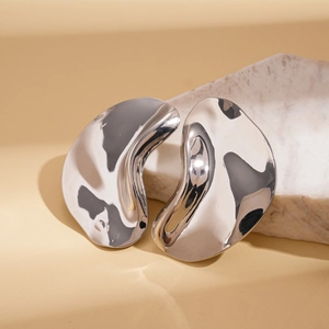 Detailed view of silver liquid metal earrings on a textured stone for a modern look