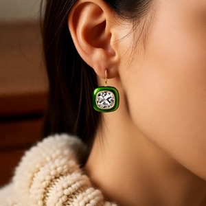 Close-up of vintage 18k gold plated square emerald earrings worn with winter knitwear