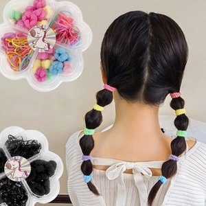 Detailed view of colorful elastic hair bands in floral boxes and a child's braided hairstyle