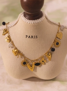 Macro view of gold multi-pendant necklace with heart, flower, and bow charms on a bust