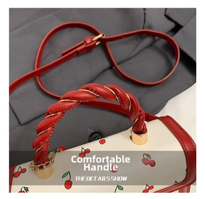 Close-up of cherry print handbag showing red twisted handle with gold wire details