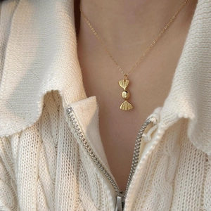 Dettaglio della collana con ciondolo a caramella in argento 925 su maglione a trecce
