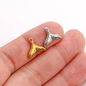 Macro shot of gold and silver whale tail pendants held on fingertips for DIY jewelry