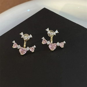 Macro detail of gold vintage earrings with pink heart crystals and white micro-zirconia