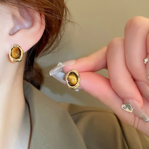 Vintage oval tiger eye stone stud earrings with gold plating shown on model ear