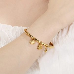 Detail of 18K gold-plated ocean-themed open bangle featuring starfish and shell charms