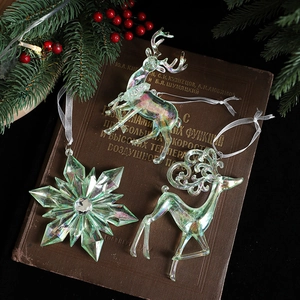 Iridescent acrylic Christmas deer and snowflake ornaments set on vintage book with lights