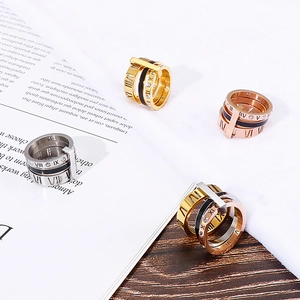 Close-up of stacked Roman numeral rings in gold, silver, rose gold and black titanium steel