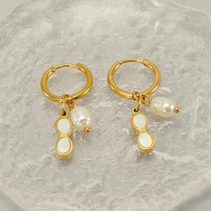 Fashion stainless steel earrings with pearl and shell pendants on a textured tray