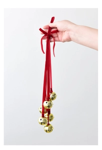 Detail of gold cutout bells with long red velvet ribbons held by hand for Christmas decoration