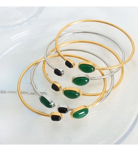 Detail of minimalist open bangles in gold and silver with black and green stone inlays