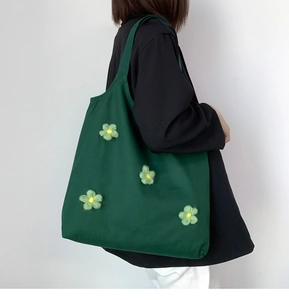 Detail of dark green canvas tote bag with 3D green flower patches on model