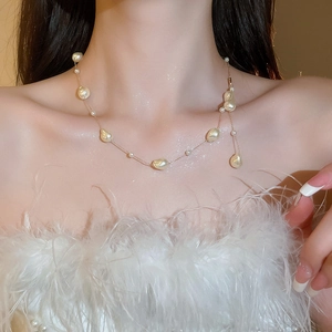 Detailed close-up of Baroque pearl necklace with gold plated chain on model neck