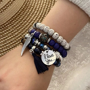 Detail of bohemian layered beaded bracelet with silver wing charm and black tassel fringe