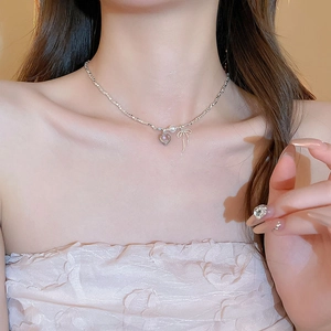 Close-up of pearl necklace with pink heart and gold bow pendant on model neck