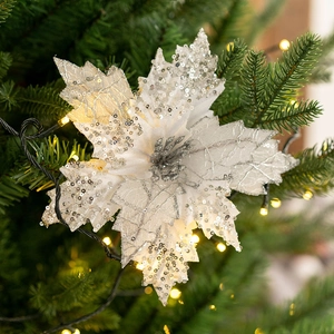 Sparkling silver artificial poinsettia with sequins on a decorated Christmas tree