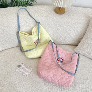 Gros plan sur des sacs cabas en coton matelassé à cœurs avec bandoulières en denim bleu