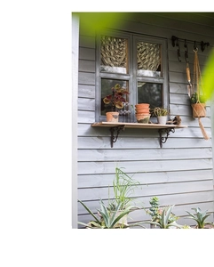 Detail of vintage cast iron bracket set supporting a wooden shelf with green plants