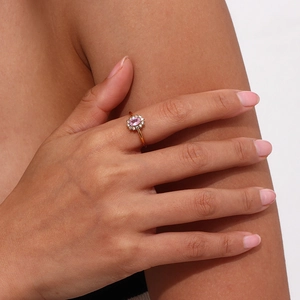 Close-up of adjustable gold ring featuring a pink oval gemstone with diamond halo