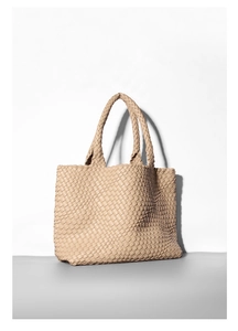 Close-up of beige woven tote bag showing luxury wide-stripe leather texture and dual handles