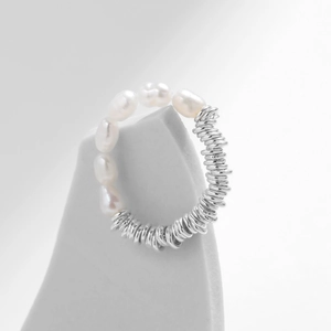 Baroque pearl and silver spiral ring displayed on a modern grey stone pedestal