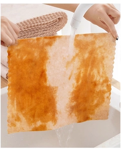 Close-up of washing a wavy-edged brown loofah cleaning cloth under running water faucet