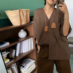 Detail of dark brown leather bell-shaped pendant accessories on a casual summer outfit