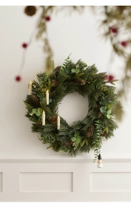 Close-up of Christmas wreath with pine cones and warm glowing LED candle lights