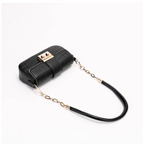 Detail of black crocodile texture bag with gold metal clasp and chain shoulder strap