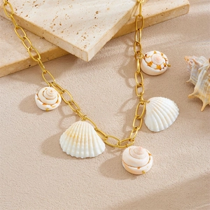 Bohemian gold chain necklace with five natural white seashell pendants on stone background