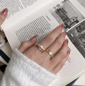Close-up of wavy gold enamel ring and zircon eternity band on hand with book background