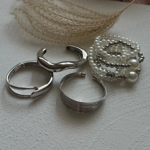 Detailed view of multilayer silver open bangles and white faux pearl beaded bracelets