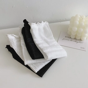 Detail of stacked black and white lace socks with textured patterns and ruffled edges