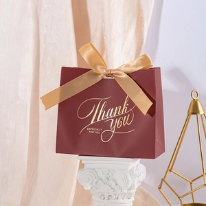 Elegant wine red gift bag with golden ribbon and Thank You gold stamping on white pillar