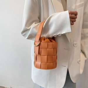 Fashionable orange woven bucket bag with stylish top handle for a summer minimalist look