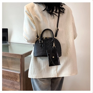 Detailed back view of a black crocodile pattern shell handbag set with gold hardware