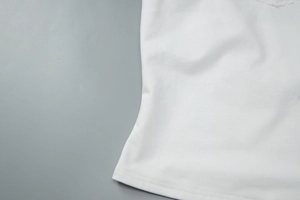 Detail of white knitted camisole showing delicate lace trim and neat bottom hem stitching