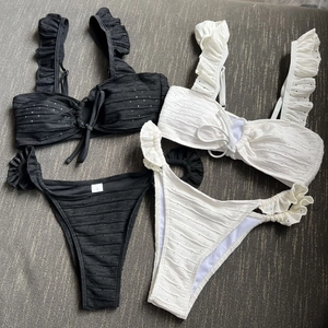 Chic ruffled bikini sets in black and white featuring lace-up front and high-cut bottoms