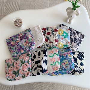 Detailed flat lay of floral cotton makeup bags and cow print pouches on a white table