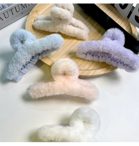 Gros plan de cinq grandes pinces à cheveux en peluche aux couleurs pastel sur bois