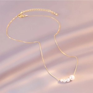 Detail of elegant gold pearl necklace with five gradient pearls on purple silk fabric