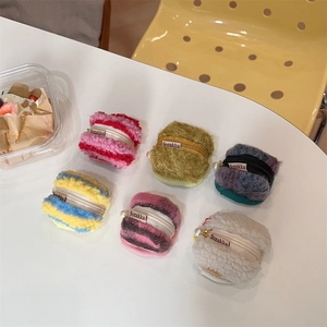 Close-up of fluffy macaron-shaped plush coin purses with zipper and pearl charms