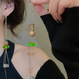 Detail of long silver tassel earrings with green and brown textured beads on model