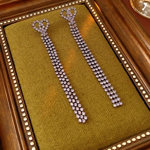 Détail de boucles d'oreilles à pompons violets avec cœur sur un cadre en tissu vintage