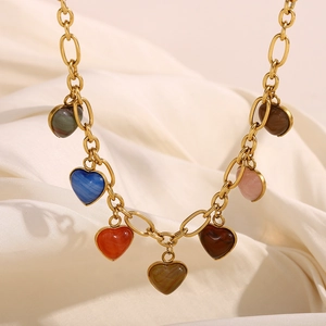 Detail of 18K gold plated chain with colorful heart pendants on beige fabric