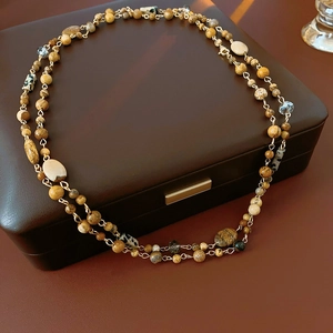 Detail of multi-layer beaded necklace with earth-tone stones and faceted glass beads