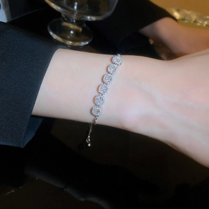 Adjustable silver bracelet with teardrop zircon pendants worn on wrist against black background
