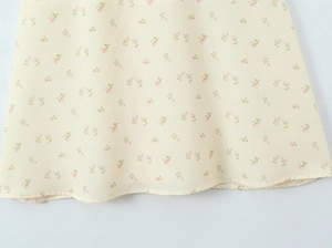 Detailed macro view of yellow floral chiffon dress hem with fine pink flower pattern