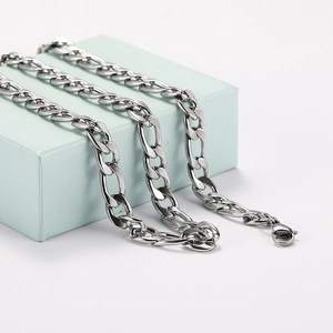 Close-up of a silver Figaro chain necklace with lobster clasp on a light blue display box