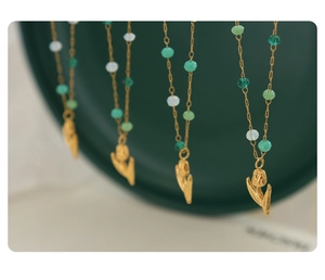 Detail view of four gold tulip pendant necklaces with green and white crystal beads